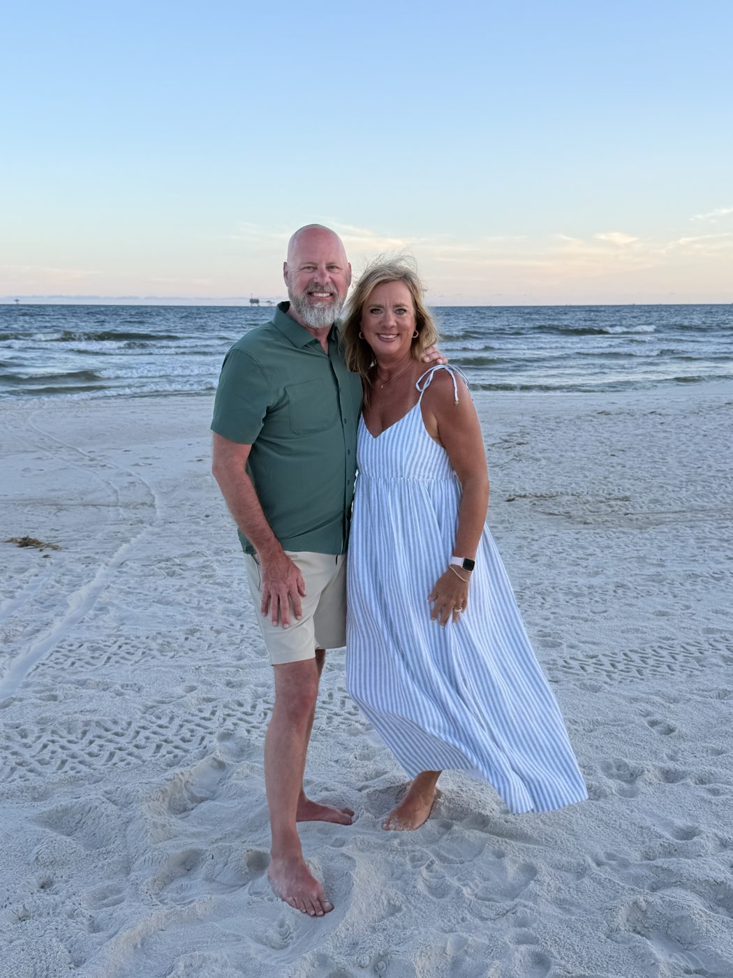 Joe and Danielle Cook standing together on a beach at sunset